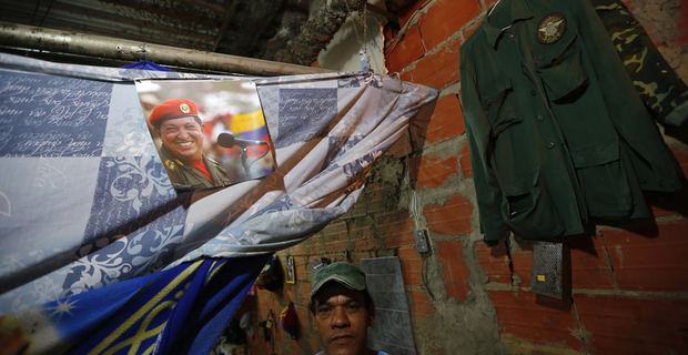 Uno degli abitanti di Torre de David posa sulla soglia del suo appartamento sotto alla foto del ex presidente Hugo Chavez. © REUTERS/Jorge Silva