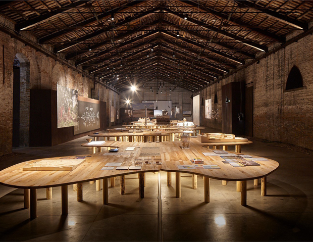 L'interno del padiglione Arcipelago Italia di Cucinella con i 5 tavoli in legno.