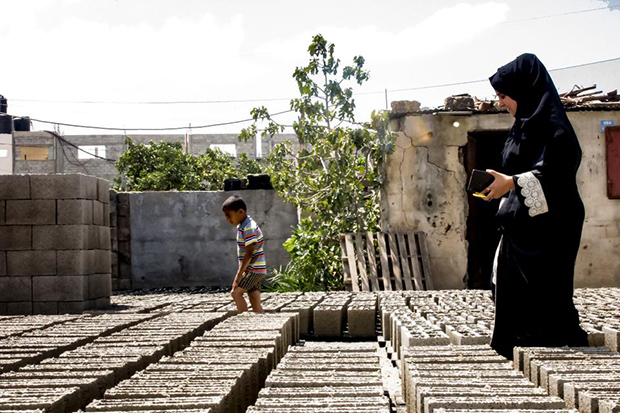  Una donna di Gaza cammina tra una distesa di mattoni Green Cake. Foto: Asmaa El Khaldi / TRTWorld