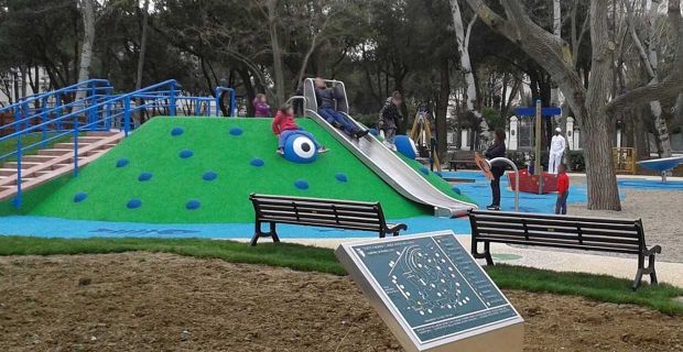  Una foto dell'area ludica dalla cui collinetta artificiale si può ammirare il parco che è interamente accessibile a tutti, dotato di vialetti percorribili dalle carrozzine, mappa tattile in Braille presso l’ingresso principale, panchine e tavolino da picnic per fare merenda tutti insieme. Nell’area sono presenti grandi alberi e diversi altri giochi come i fiori parlanti, il disco rotante, tre tipi di altalene, e altri giochi e arredi per tutte le esigenze.